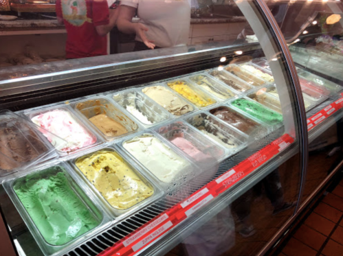 A display case filled with various colorful ice cream flavors in metal containers.