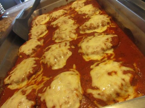 A tray of baked chicken covered in marinara sauce and melted cheese.