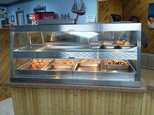 A stainless steel food display case with various trays of fried chicken and sides in a casual dining setting.