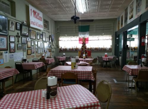 Cozy restaurant interior with checkered tablecloths, decorated walls, and a festive display in the corner.