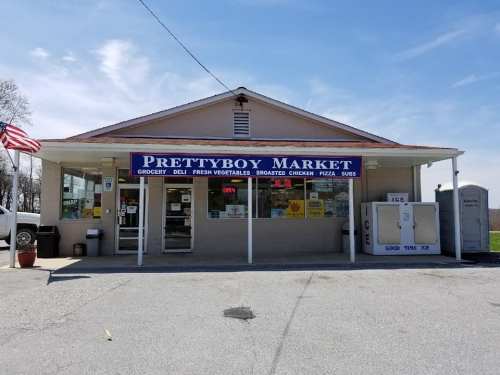 Exterior of Prettyboy Market, a grocery store with a deli, fresh vegetables, and a sign indicating it's open.