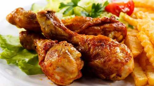 A plate of crispy chicken drumsticks served with lettuce, tomato, and French fries.