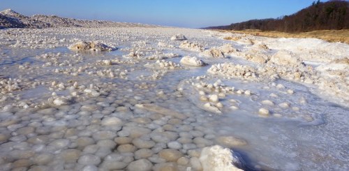 A frozen landscape with large ice formations and a clear blue sky in the background.