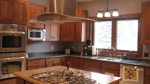 Modern kitchen with wooden cabinets, stainless steel appliances, and a large window above the sink.