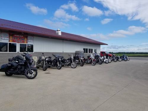 A row of motorcycles parked outside a building under a blue sky with scattered clouds.