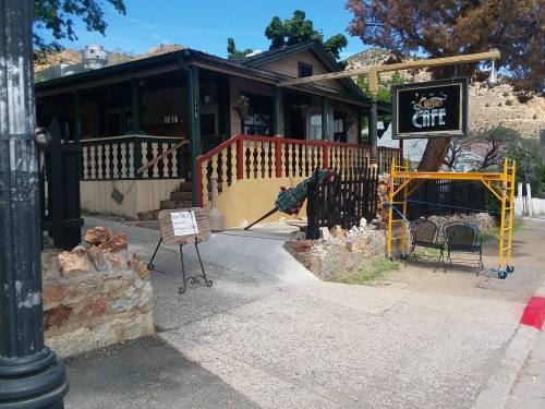 A quaint café with a wooden porch, surrounded by stone walls and scaffolding, set in a scenic outdoor area.
