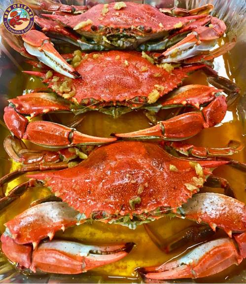 Three cooked crabs seasoned and arranged in a tray with a flavorful sauce.
