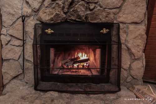 A cozy stone fireplace with a crackling fire and logs, creating a warm and inviting atmosphere.