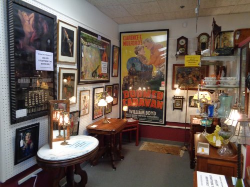 A cozy antique shop filled with vintage artwork, posters, lamps, and furniture, creating a nostalgic atmosphere.