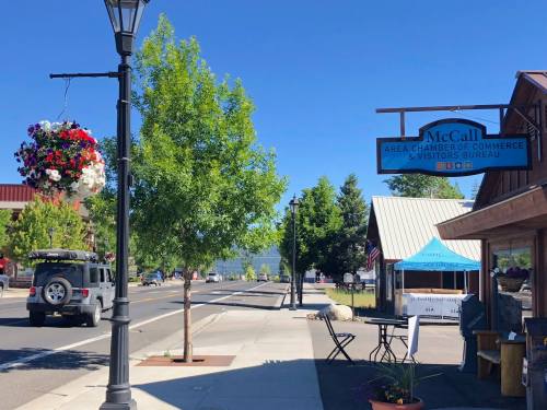 Street view of McCall, Idaho, featuring the Chamber of Commerce, hanging flower baskets, and a parked jeep.