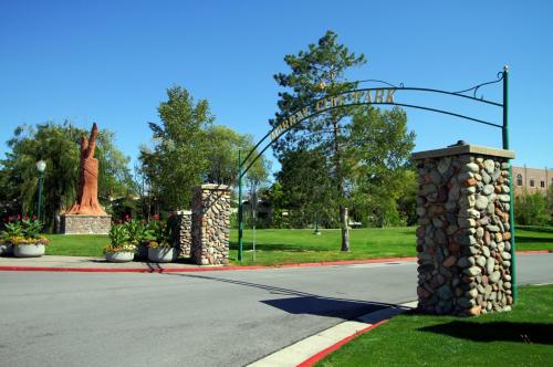 Entrance to Murray City Park featuring a stone archway and a large statue, surrounded by greenery and flowers.
