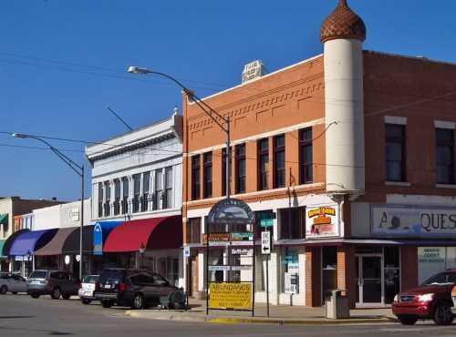 Historic downtown buildings with colorful awnings and signage under a clear blue sky.