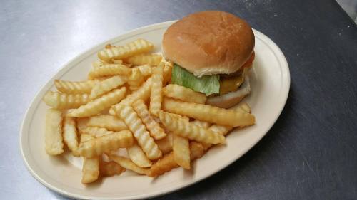 A plate of crinkle-cut fries next to a hamburger with lettuce, tomato, and cheese on a bun.