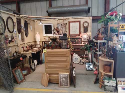 A cozy antique shop display featuring various vintage items, furniture, and decorative pieces arranged on shelves and tables.