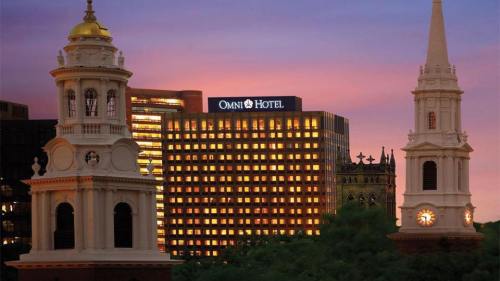 City skyline at sunset featuring the Omni Hotel and historic church towers.