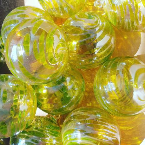 A close-up of vibrant green and yellow glass ornaments with swirling patterns, arranged closely together.
