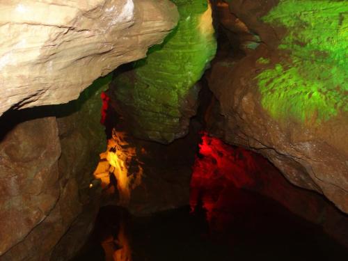 Colorful cave interior with illuminated rock formations and a reflective water surface.