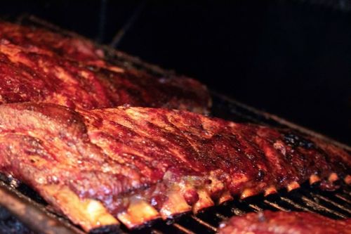 Close-up of juicy, smoked ribs on a grill, showcasing a rich, caramelized glaze and tender meat.