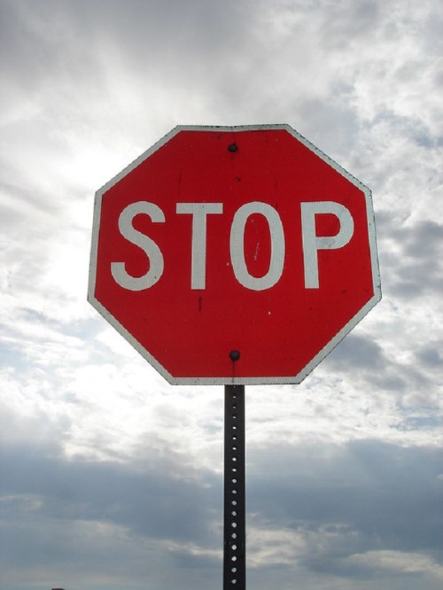 A red octagonal stop sign against a cloudy sky.
