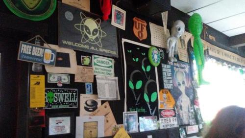 A wall covered in quirky alien-themed posters, signs, and memorabilia, creating a playful, otherworldly atmosphere.