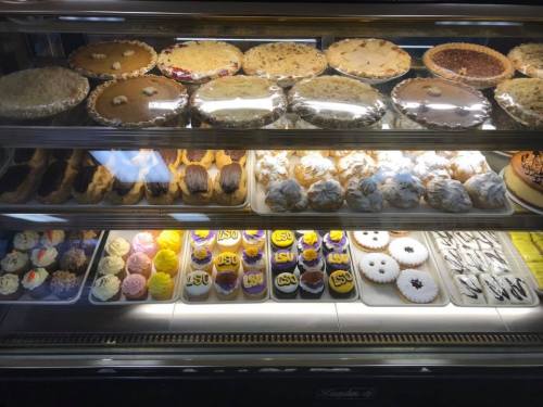 A display case filled with various desserts, including pies, cupcakes, and cookies, showcasing colorful treats.