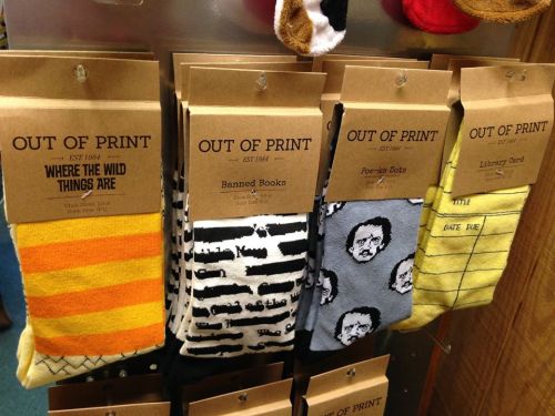 Display of colorful socks with literary themes, featuring designs like "Where the Wild Things Are" and "Banned Books."
