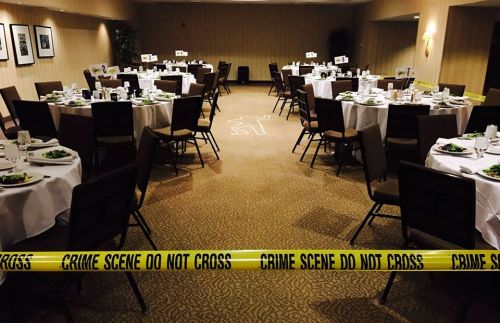 A dining room set for a meal, with tables, plates, and a "crime scene do not cross" tape across the area.