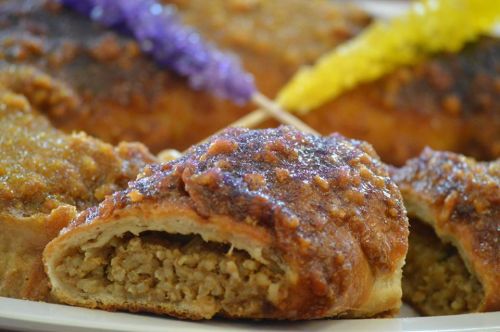 A close-up of a golden-brown pastry filled with a savory mixture, garnished with colorful decorative sticks.