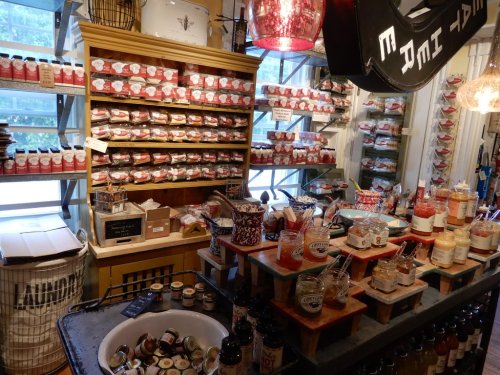 A cozy shop interior filled with jars and packaged goods on shelves, with a rustic counter displaying various items.