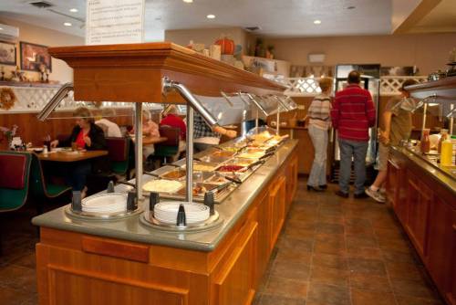 A buffet setup with various food options, diners enjoying meals, and a cozy restaurant atmosphere.