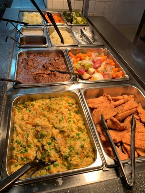 A buffet with various dishes: mashed potatoes, vegetables, beef, mixed veggies, rice, and fried chicken.