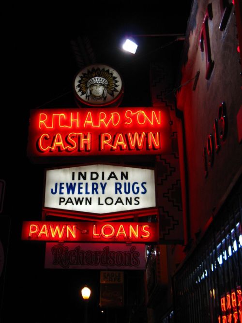 Neon sign for Richardson Cash Pawn, featuring "Indian Jewelry Rugs" and "Pawn Loans" in bright red and white lights.