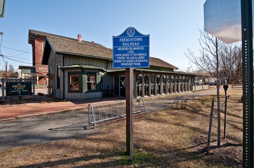 Historic sign for the Frenchtown Railroad in front of a building, with grassy area and bike rack nearby.