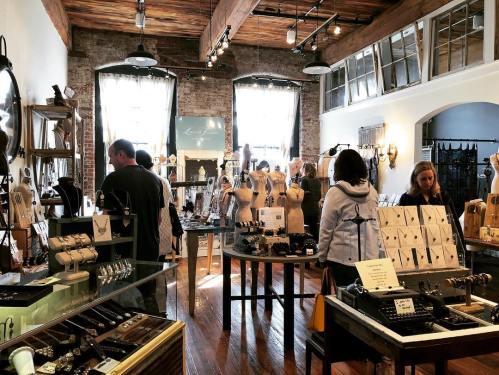 A jewelry store interior with customers browsing displays of necklaces, bracelets, and earrings in a rustic setting.