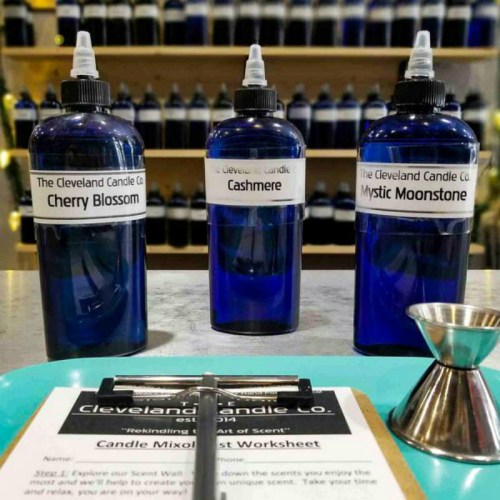Three blue bottles labeled "Cherry Blossom," "Cashmere," and "Mystic Moonstone" on a table with a worksheet.