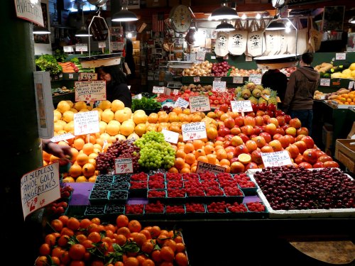 A vibrant market display featuring a variety of fruits, including apples, oranges, grapes, and berries, with price signs.