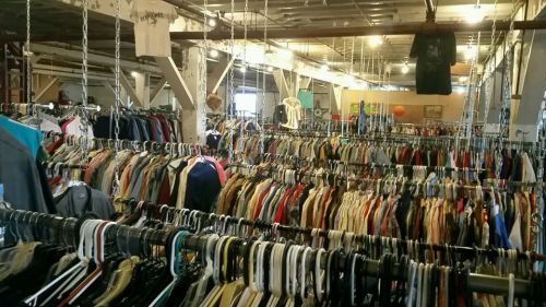 A large thrift store filled with rows of hanging clothes on racks, showcasing a variety of colors and styles.
