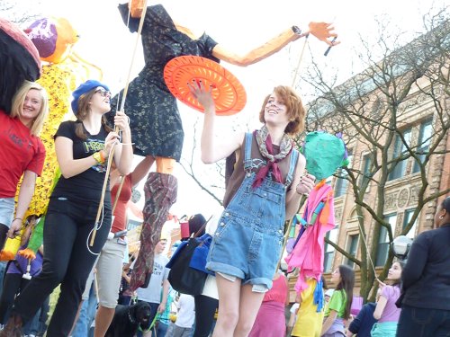 A group of people joyfully parading with colorful puppets and costumes during a festive event.