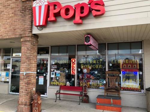 Exterior of Pop's shop featuring a popcorn sign, open window, and festive decorations.