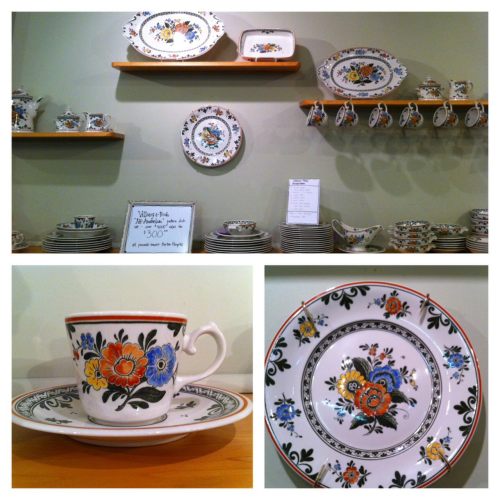 A display of colorful floral-patterned ceramic dishware on shelves, including plates and a teacup.