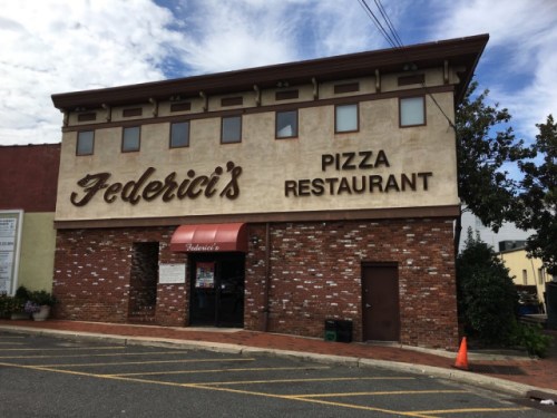 Exterior of Federici's Pizza Restaurant, featuring a brick facade and large signage, with a cloudy sky above.