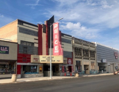 Historic theater building with a marquee displaying "Fast and the Furious" and "Hobbs and Shaw," set against a blue sky.