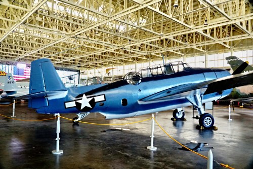 A vintage military aircraft displayed indoors, featuring a blue exterior and a star insignia on its side.