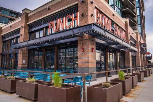 Exterior of Punch Bowl Social, featuring large signage, outdoor seating, and modern architecture.