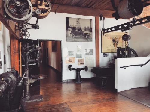A vintage industrial space featuring old machinery, wooden beams, and historical photographs on the walls.