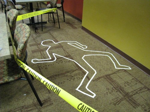A chalk outline of a body on the floor, surrounded by caution tape in a restaurant setting.
