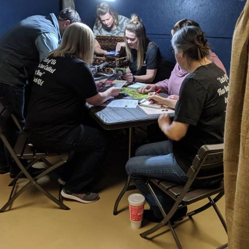 A group of people gathered around a table, engaged in a collaborative activity in a dimly lit room.