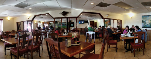 A spacious restaurant interior with wooden tables, patrons dining, and a warm, inviting atmosphere.