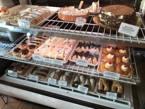 A display case filled with various pastries and desserts, including cakes, tarts, and cream-filled treats.