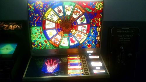 A colorful vintage arcade game with a spinning wheel and various symbols, featuring bright artwork and buttons.